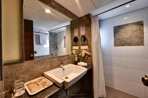 ein Bad mit einem Waschbecken und einem Spiegel in der Unterkunft Click Hotel Vadodara 2 Mins from Railway Station in Vadodara