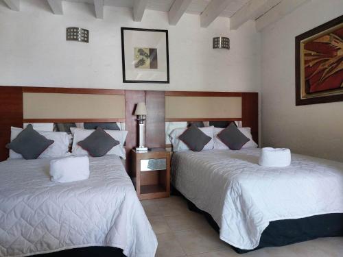 sypialnia z 2 łóżkami z białą pościelą i niebieskimi poduszkami w obiekcie Casa de la O w mieście Yautepec