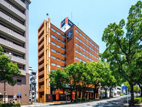 a tall building on a city street with trees at APA Hotel Nagasaki Dejima in Nagasaki