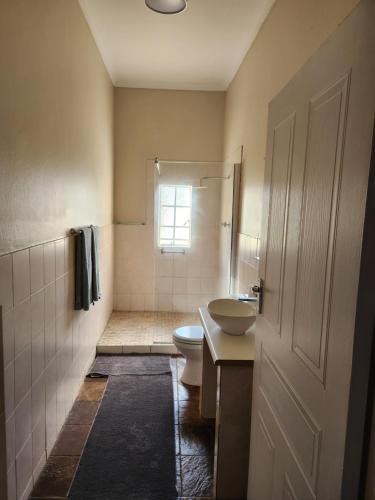La salle de bains est pourvue de toilettes et d'un lavabo. dans l'établissement Guest Room, à Boksburg