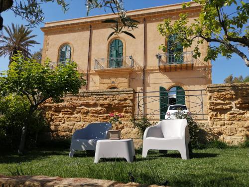 dos sillas y una mesa frente a un edificio en A casa di Mammì nella Valle dei templi, en Agrigento