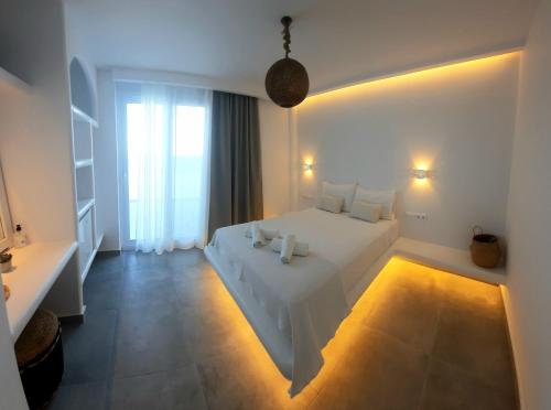 a white bedroom with a white bed and a window at Paros Blue Dolphin FULLY RENOVATED by RIVEA GROUP in Chrissi Akti