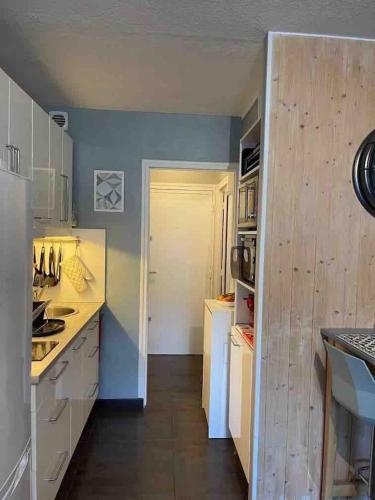 a kitchen with white cabinets and a blue wall at studio ponant avec parking climatisé in La Grande-Motte