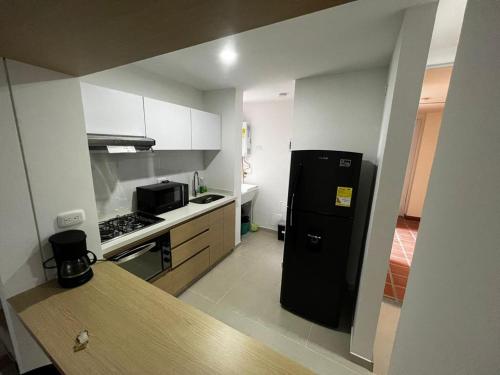a kitchen with a black refrigerator and a stove at Hermoso apartamento la Francia 3 habitaciones in Manizales