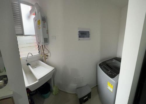 baño blanco pequeño con lavabo y ventana en Hermoso apartamento la Francia 3 habitaciones, en Manizales