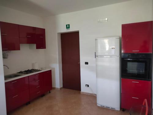 a kitchen with red cabinets and a white refrigerator at Agriturismo Sant'Anna Ortì in oliveta biologica con vista sullo Stretto di Messina in Orti