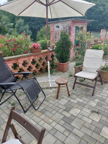 a patio with two chairs and an umbrella at Casa relax immersa nel verde della natura in Casalborgone