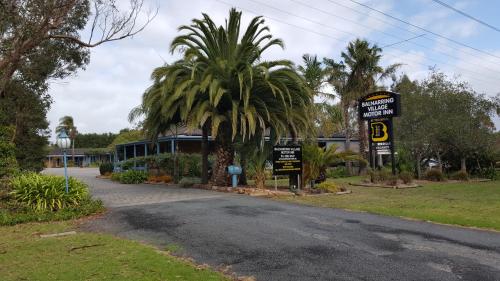 a street sign with a palm tree and a building at The Balnarring Motel in Balnarring