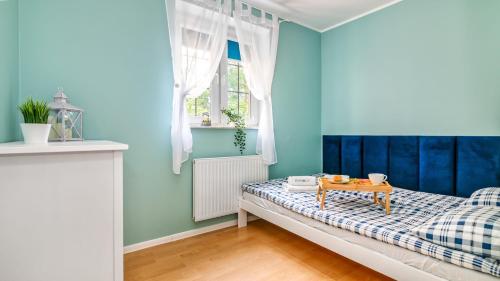 - une chambre avec des murs bleus et un lit avec une table dans l'établissement Teleexpresu Apartamenty PIAMOLA, à Krynica Morska