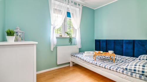 a bedroom with blue walls and a bed with a table at Teleexpresu Apartamenty PIAMOLA in Krynica Morska
