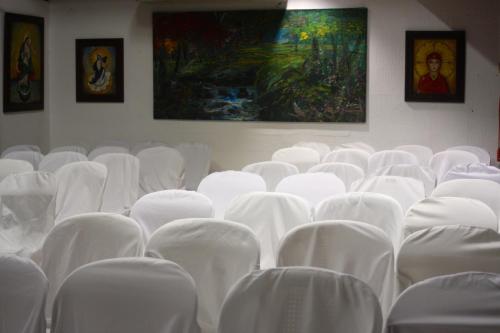 a room with white chairs and paintings on the wall at La Posada del Arcangel in Managua