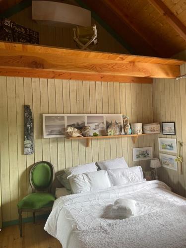 um quarto com uma cama e uma cadeira verde em La Cabane em Andernos-les-Bains