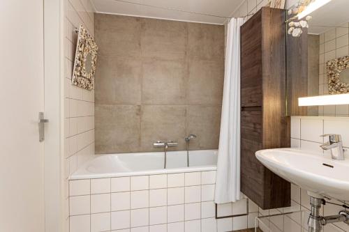 een witte badkamer met een bad en een wastafel bij Villa Veerse Meer in Kamperland