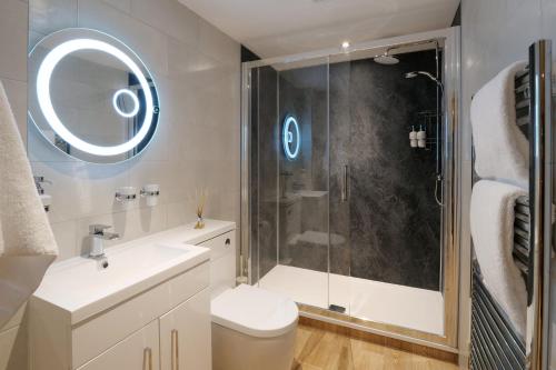 a bathroom with a shower and a toilet and a sink at Pinetum Garden Cottages in St Austell