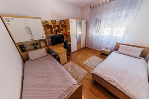 mały pokój z 2 łóżkami i telewizorem w obiekcie Luka w mieście Kaštela
