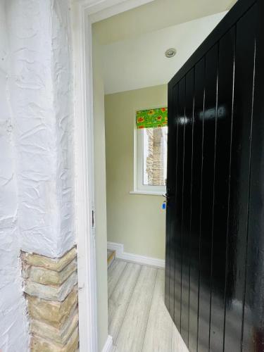 a hallway with a black door and a window at Pentre Cerrig Country House in Llanferres