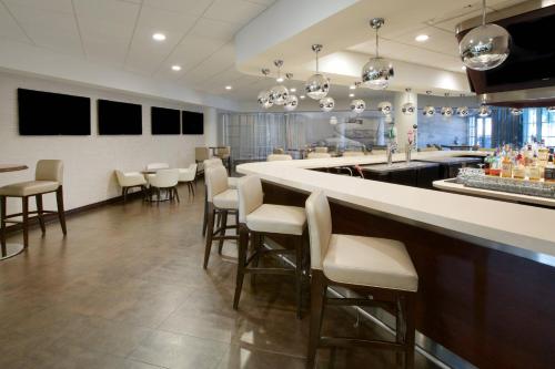 a bar in a restaurant with white chairs and a counter at Sheraton Miami Airport Hotel and Executive Meeting Center in Miami