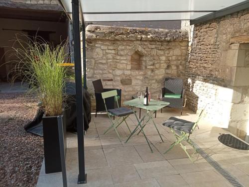a patio with a table and chairs and a stone wall at L'instant Civray in Civray-sur-Esves