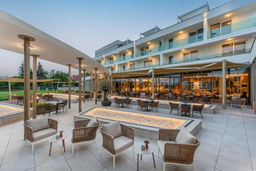 uma vista exterior de um hotel com mesas e cadeiras em Hotel Vinifera Wine & Spa 5 Stars Superior em Balatonfüred