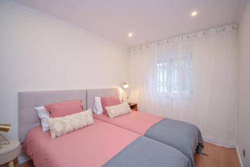 um quarto com uma cama grande, cor-de-rosa e azul em Amor a mar em Sesimbra