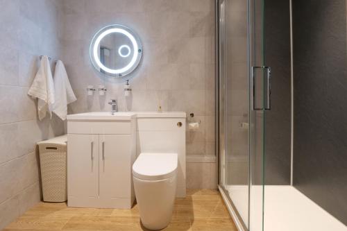 a bathroom with a toilet and a sink and a shower at Pinetum Garden Cottages in St Austell