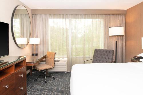 a hotel room with a desk and a mirror at Sheraton Ann Arbor Hotel in Ann Arbor