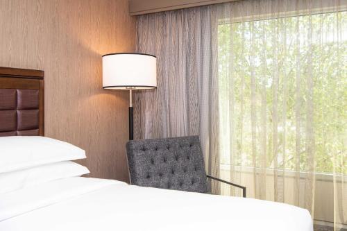 a bedroom with two beds and a chair and a window at Sheraton Ann Arbor Hotel in Ann Arbor