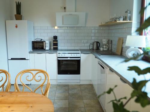 kuchnia z białymi urządzeniami oraz stołem i krzesłami w obiekcie Apartamenty Świętego Wita w Żywcu
