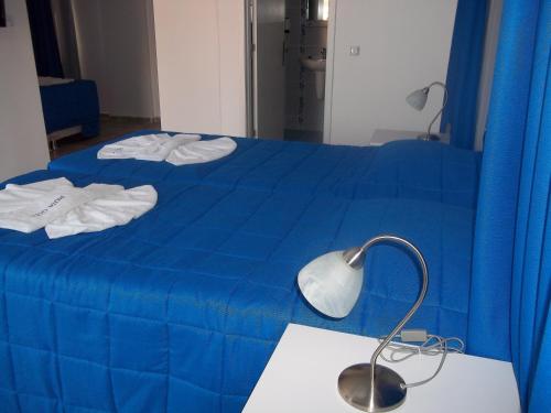 a blue bed with blue sheets and a desk with a lamp at Rota Hotel in Dalyan