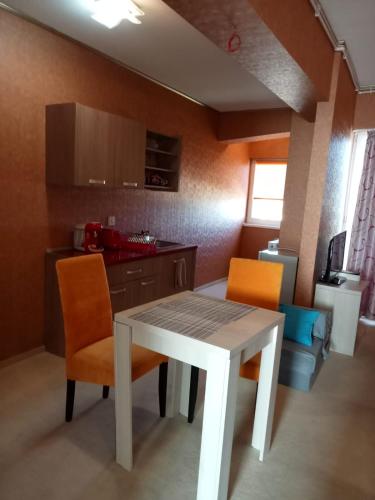 uma cozinha com uma mesa branca e 2 cadeiras laranja em apartament bloc joylife 18 em Costinesti