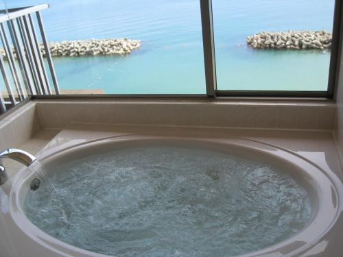 a bath tub with a view of the ocean at Hakusen in Yonago