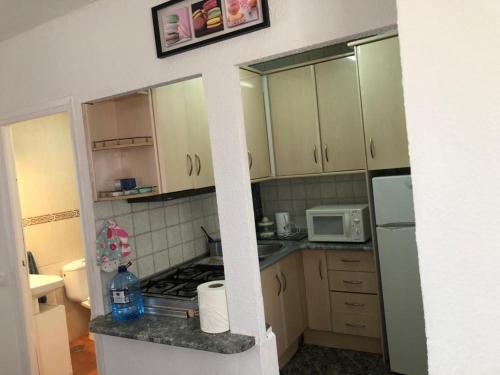 una piccola cucina con armadietti bianchi e forno a microonde di bungalows Santa Pola a Gran Alacant
