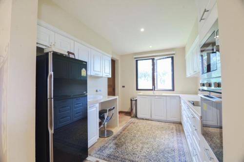 a kitchen with white cabinets and a black refrigerator at Private Pool Villa & Golf - Toscana House Khaoyai 4 Bedrooms 10 Guests in Ban Rai Khlong Sai
