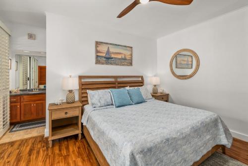 a bedroom with a bed and a mirror on the wall at Step to beach New Quiet Kiahuna Plantation Remodeled 2 bedroom condo with AC in Koloa