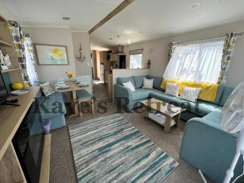 a living room with a blue couch and a table at Kayes Retreat Three bed caravan Newquay Bay Resort Quieter area of park in Newquay