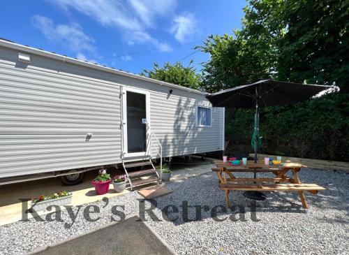 a picnic table and an umbrella next to a trailer at Kayes Retreat Three bed caravan Newquay Bay Resort Quieter area of park in Newquay