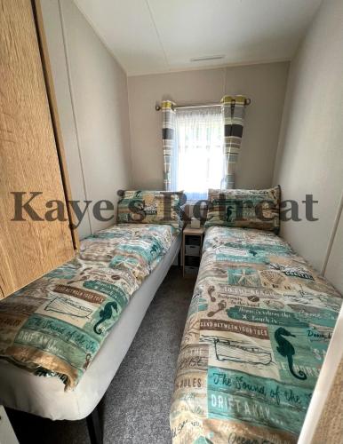 two beds in a small room with a window at Kayes Retreat Three bed caravan Newquay Bay Resort Quieter area of park in Newquay