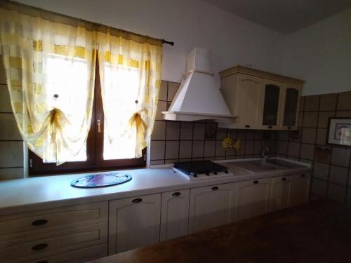 a kitchen with a sink and a window with curtains at Il Villino in Platamona