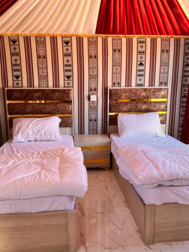 two beds in a room with a wall at Wadi Rum Sand Camp in Disah