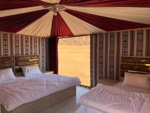 a bedroom with two beds and a large window at Wadi Rum Sand Camp in Disah