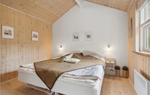 - une chambre avec un lit dans une pièce dotée de murs en bois dans l'établissement Amazing Home In lbk With Kitchen, à Ålbæk