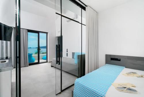 a bedroom with a blue and white bed and a bathroom at Mythodea Prive Luxury Suites in Chrysi Ammoudia