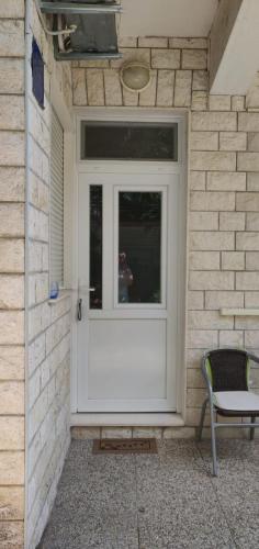 a white door on a brick building with a chair at Omis apartment - near beach and town center, ground floor with small garden in Omiš