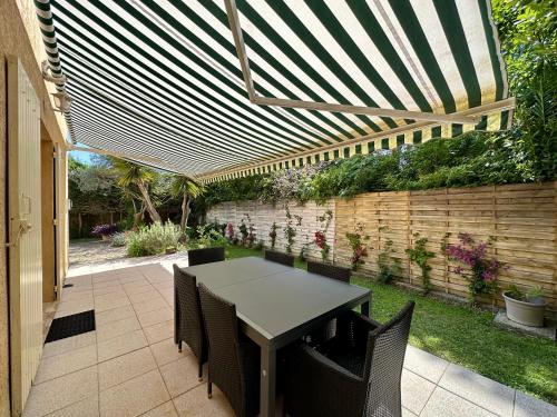 d'une terrasse avec une table et des chaises sous une pergola. dans l'établissement Villa Marinette, à Juan-les-Pins