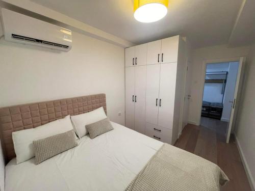 a bedroom with a large bed with white cabinets at Promenada Apartment in Novi Sad