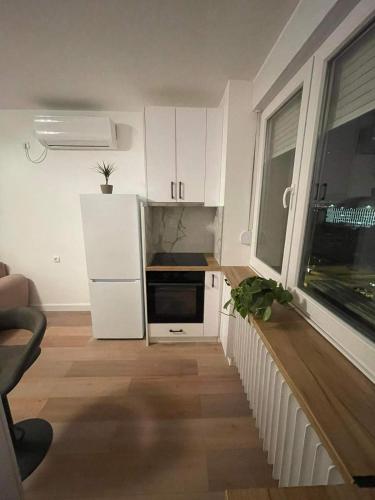 a small kitchen with white cabinets and a window at Promenada Apartment in Novi Sad