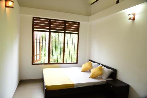 a bedroom with a bed with yellow pillows and a window at Sadisa Villa in Hikkaduwa
