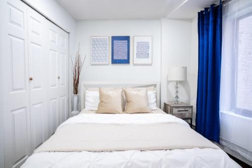 um quarto branco com uma cama grande e cortinas azuis em 809-3B Columbus Circle W D new BLDG Balcony em Nova Iorque