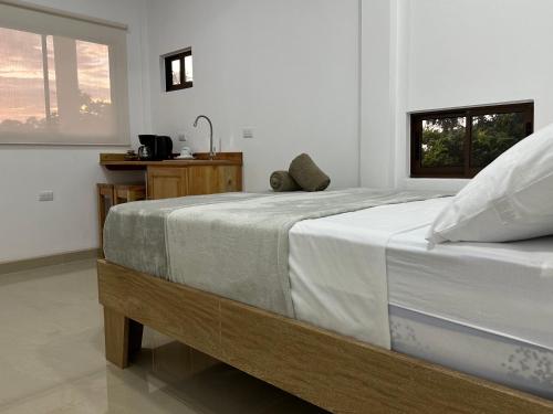 a bedroom with a large bed with white sheets at Tuanis Guest House in Tortuguero