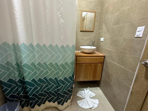 a bathroom with a shower curtain and a sink at Tuanis Guest House in Tortuguero